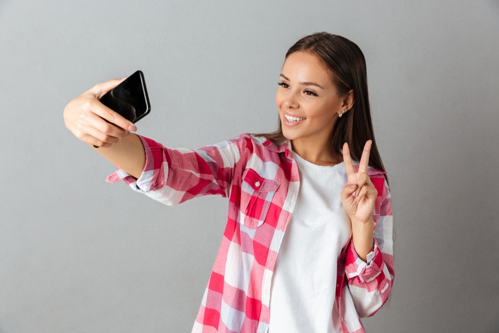photo-joyful-young-woman-checkered-shirt-taking-selfie-by-her-phones.jpg