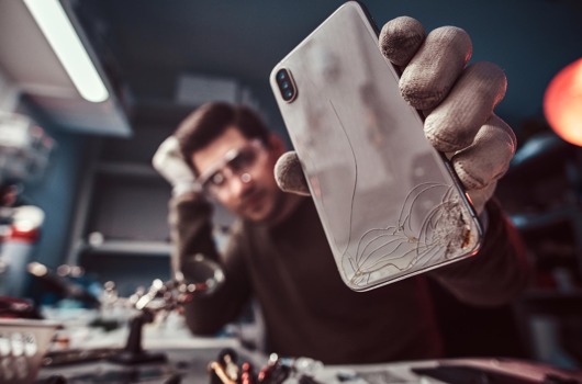 electronic-technician-showing-modern-smartphone-with-broken-body-repair-shop.jpg